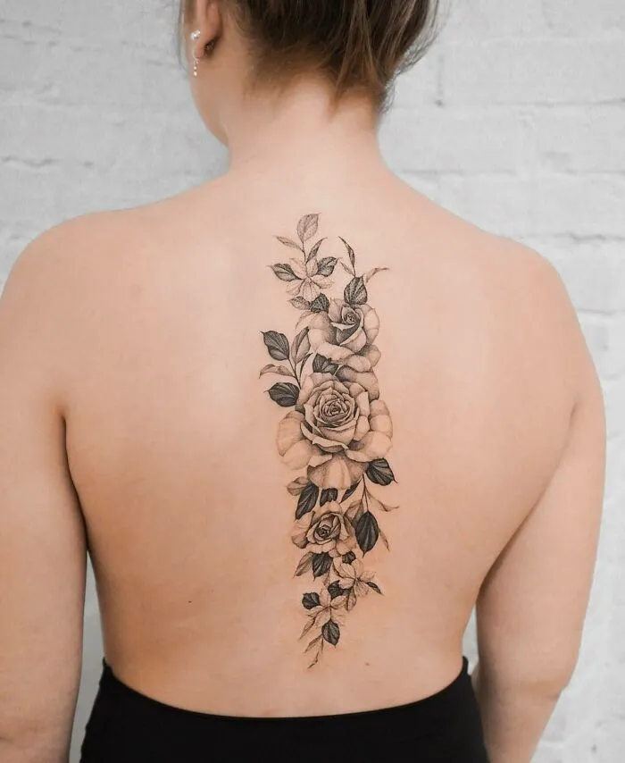 Elegant spine tattoo of floral design on a woman's back, showcasing intricate patterns and delicate artistry.