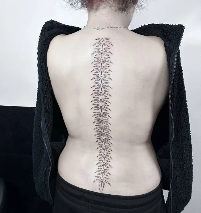 Elegant spine tattoo design with intricate patterns on a person's back, showcasing stylish ink art for men and women.