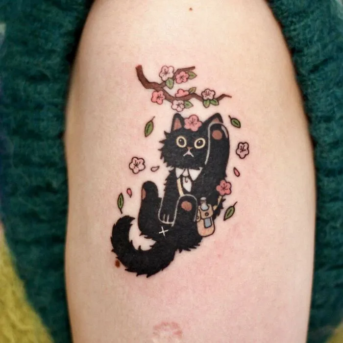 Tattoo of a black cat with flowers and branches, showcasing adorable animal-themed design.