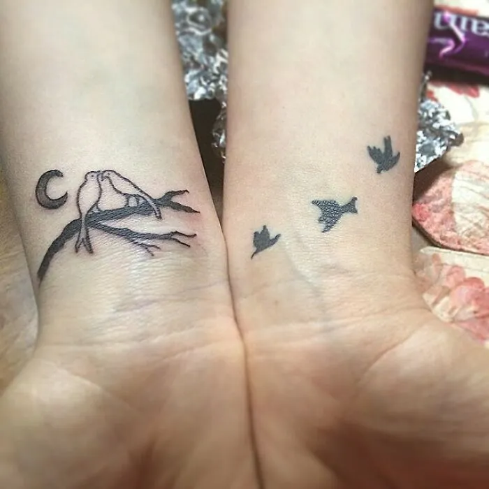 Wrist tattoo design featuring birds on a branch and flying silhouettes, showcasing creative wrist tattoo ideas.