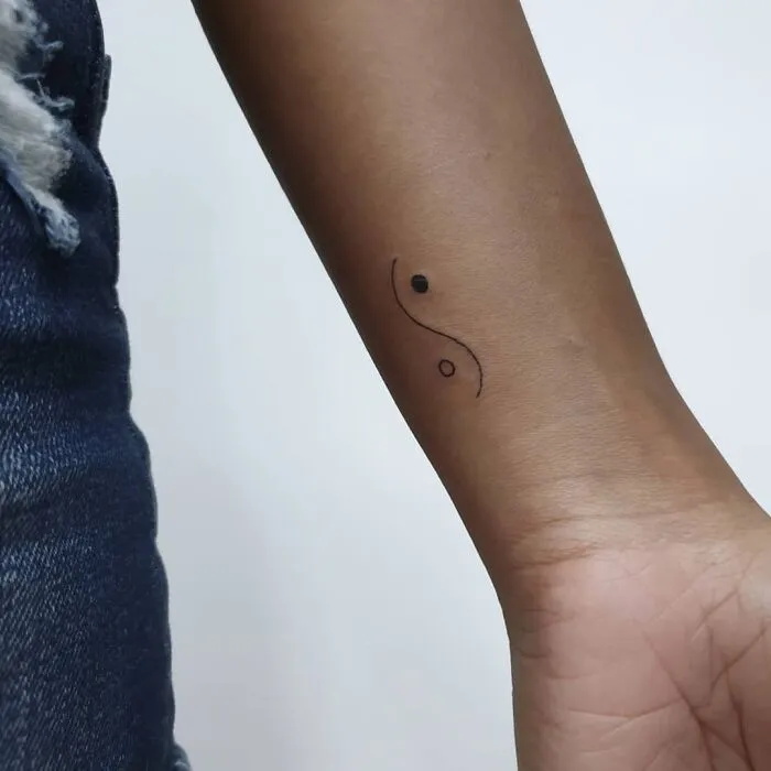 Simple wrist tattoo design featuring a minimalist yin-yang symbol, showcasing modern wrist tattoo artistry.