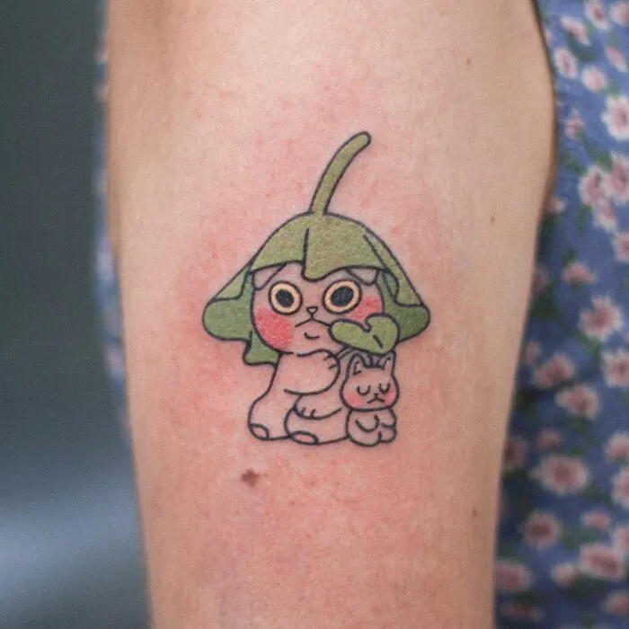 Adorable animal-themed tattoo featuring a cute creature with a leafy hat, designed by a tattoo artist.