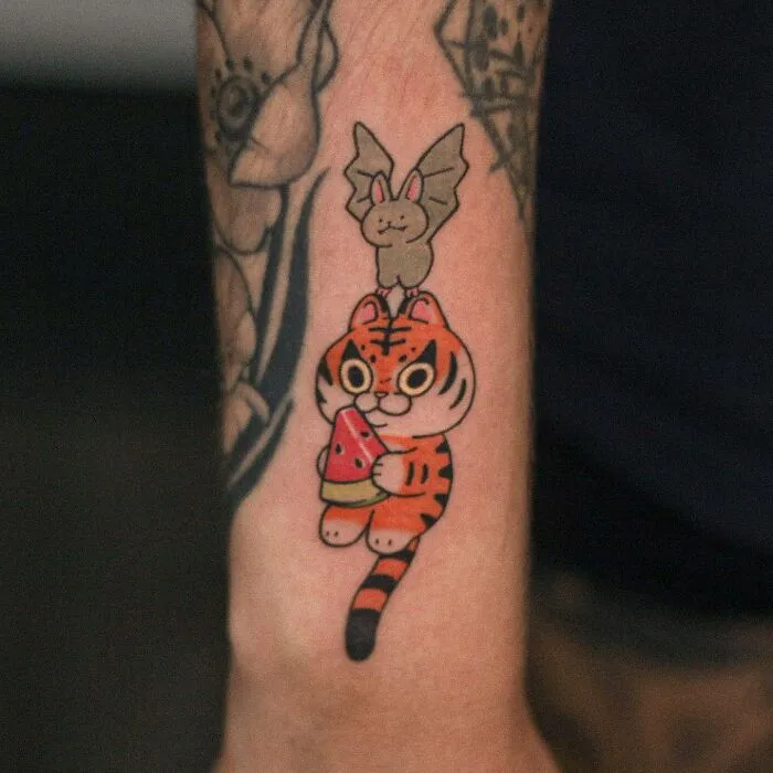 Tattoo featuring an adorable tiger and bat design, showcasing animal-themed artistry on an arm.