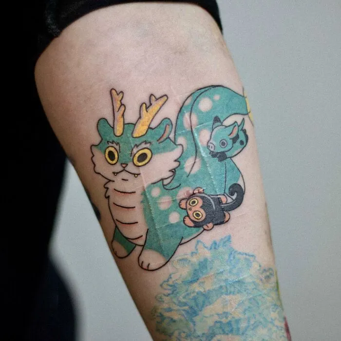 Animal-themed tattoo design featuring cute, colorful creatures on an arm.