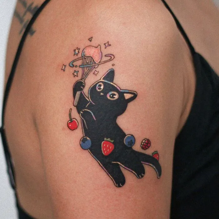 Tattoo of an adorable cat with fruits, showcasing animal-themed design on a person's arm.