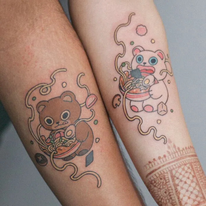 Tattoo artist designs adorable animal-themed tattoos on two arms, featuring bears with noodles and playful colors.
