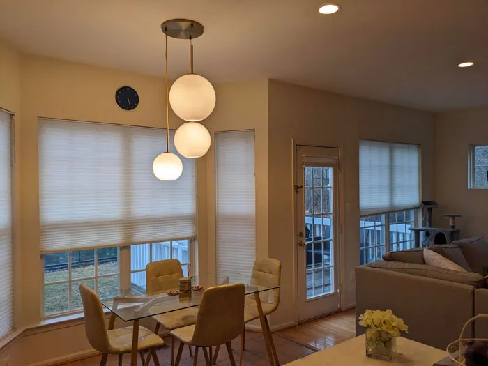 Modern dining area with chic pendant lights, glass table, and beige chairs—home decoration ideas for a stylish interior.