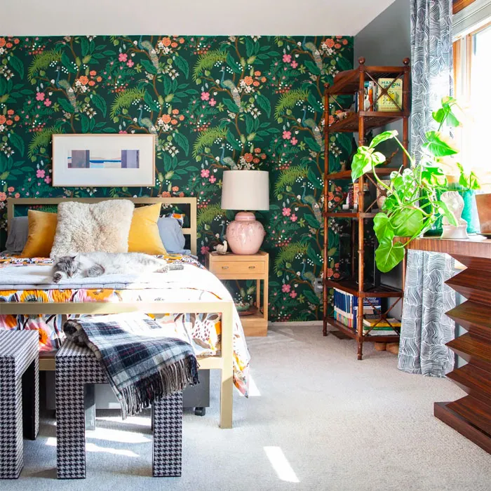 Bedroom with floral wallpaper, colorful pillows, bookshelves, and green plants adding to home decoration ideas.