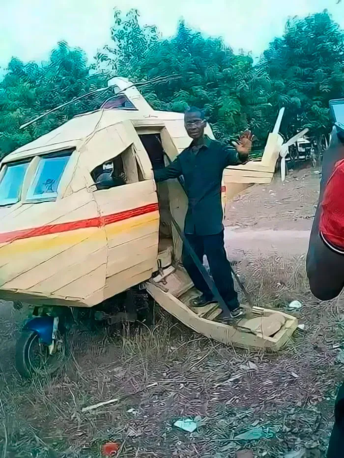 Man standing by a handmade helicopter, capturing an important image in a rural setting.
