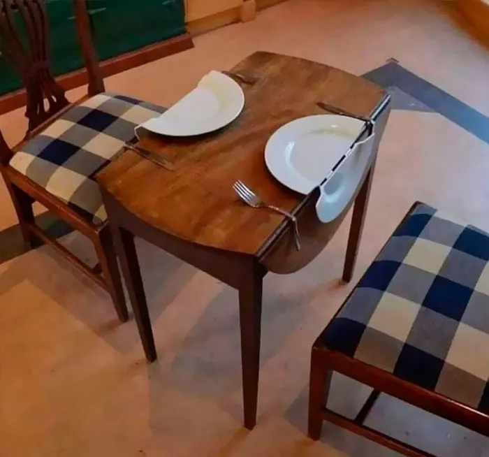 Two plates cut in half on a small table set for dining, creating an unhinged optical illusion.