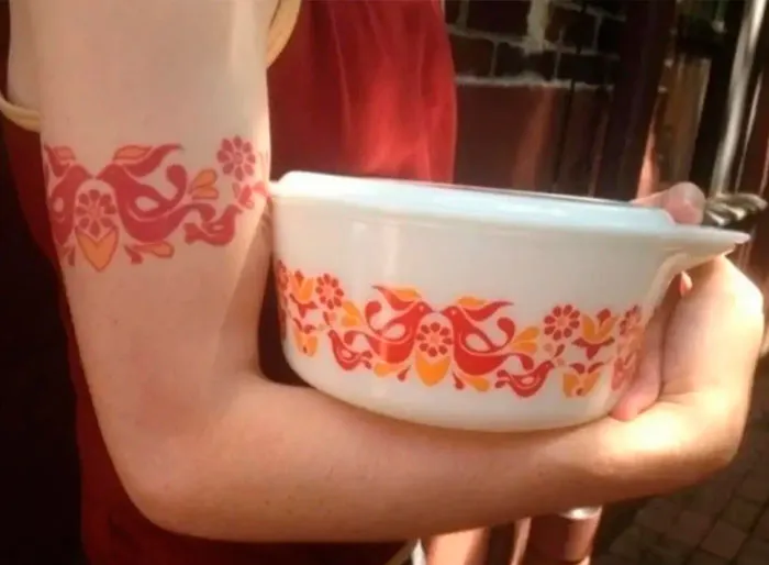 Person holding a dish with a matching pattern tattooed on their arm, showcasing an important image.