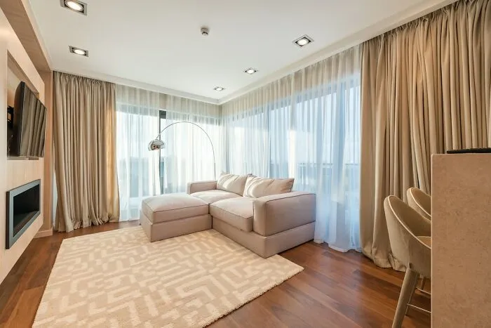 Modern living room with beige sectional sofa, stylish floor lamp, and elegant curtains, exemplifying home decoration ideas.