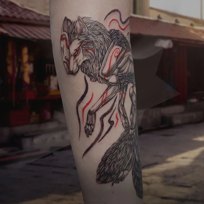 Red ink tattoo of an intricate wolf design on a forearm in an urban setting.