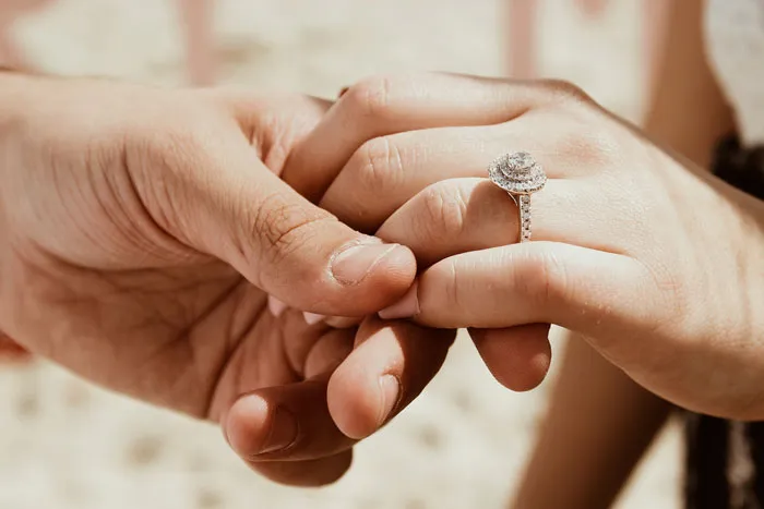 Two people holding hands, highlighting relationship myths, with one wearing an engagement ring.