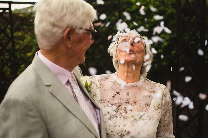 Elderly couple enjoying a moment outdoors, surrounded by flower petals, symbolizing timeless relationship myths.