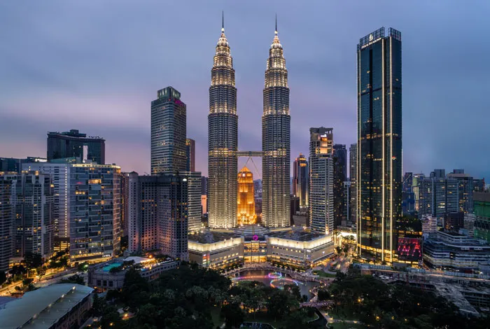Two the same tall buildings lighted up at night 