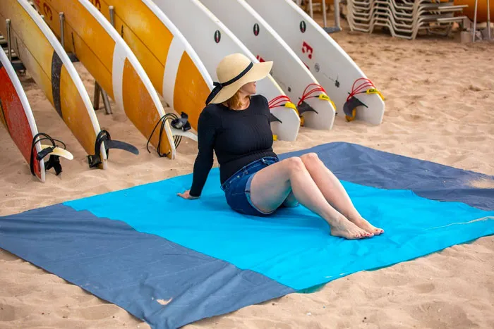 Woman sitting on the blue beach mat 