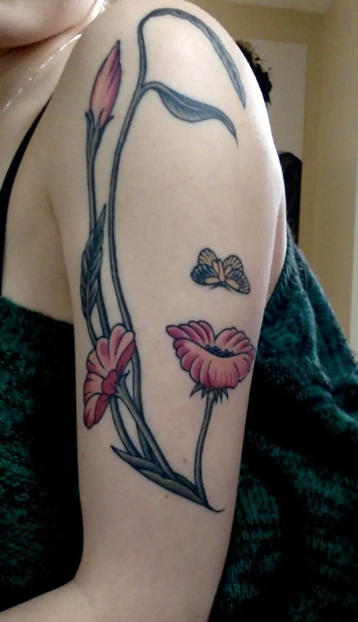 Floral tattoo on arm with butterfly, showcasing optical illusion tattoo design.