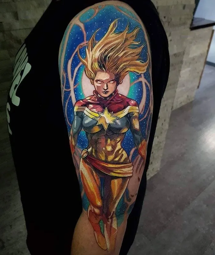 Marvel tattoo of superhero Captain Marvel on an arm, featuring vibrant colors and dynamic design.