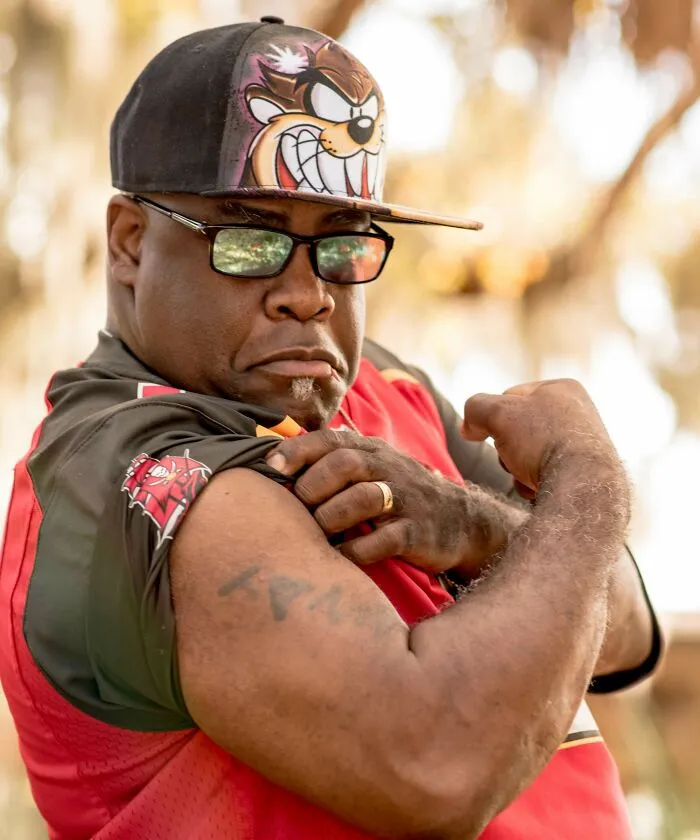 A man wearing sunglasses showing how strong he is 