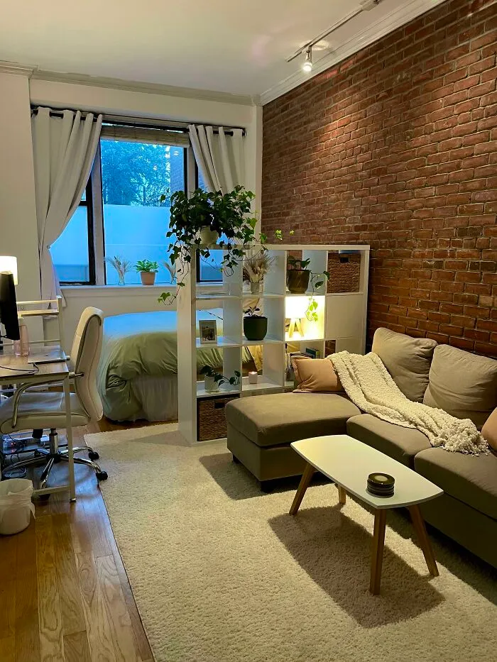 Grey couch next to a brick wall 