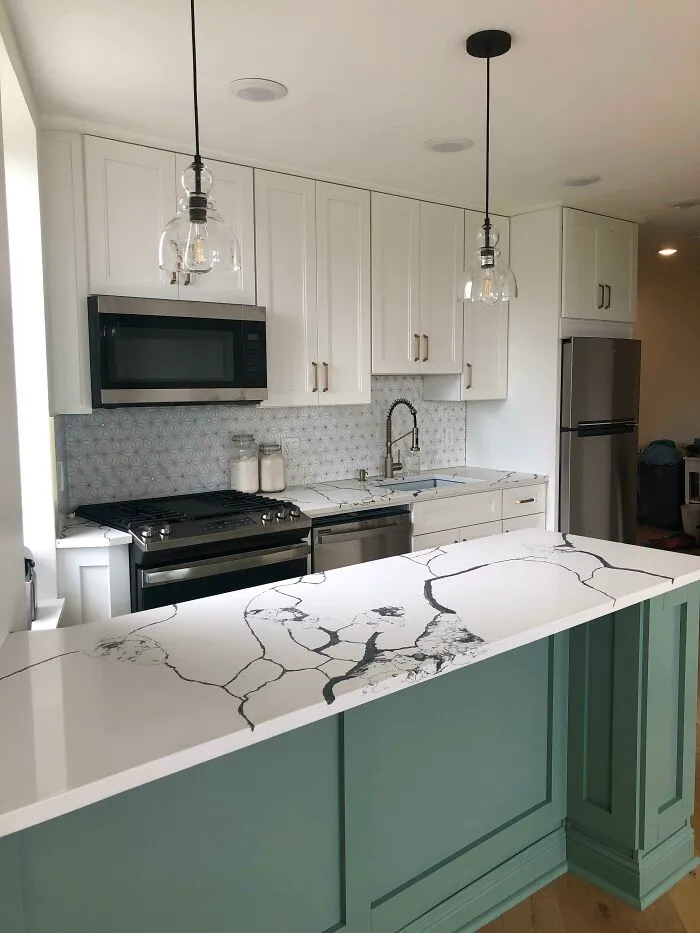 White and green kitchen cabinets with marble surface 