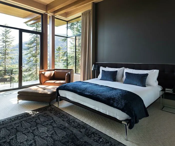 Black bedroom with a black bed and brown chair 