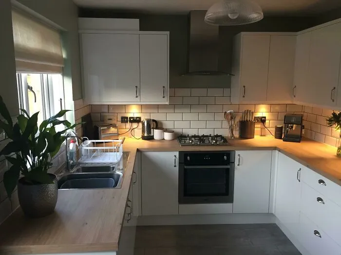 White kitchen cabinets with wooden surface 