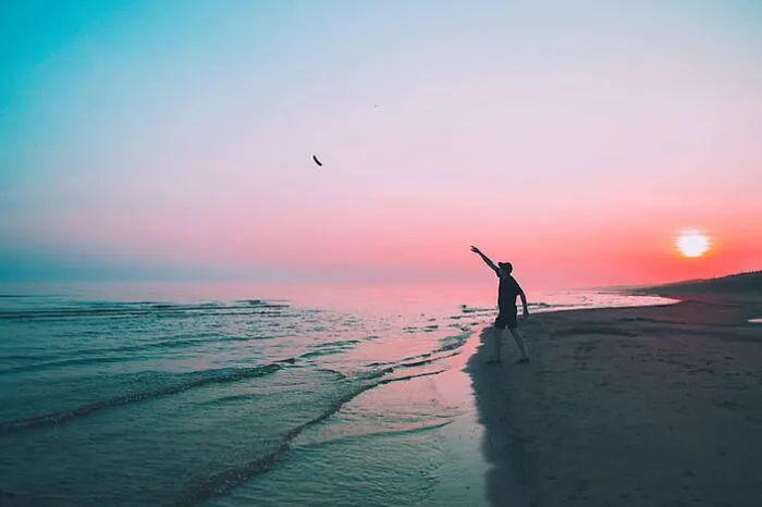 Man throwing a boomerang in to the water 