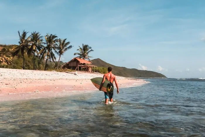 Man walking with a surfboard in the beach 