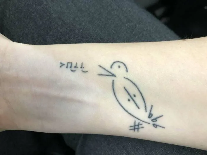Minimalist music tattoo of a bird and music notes on a wrist.