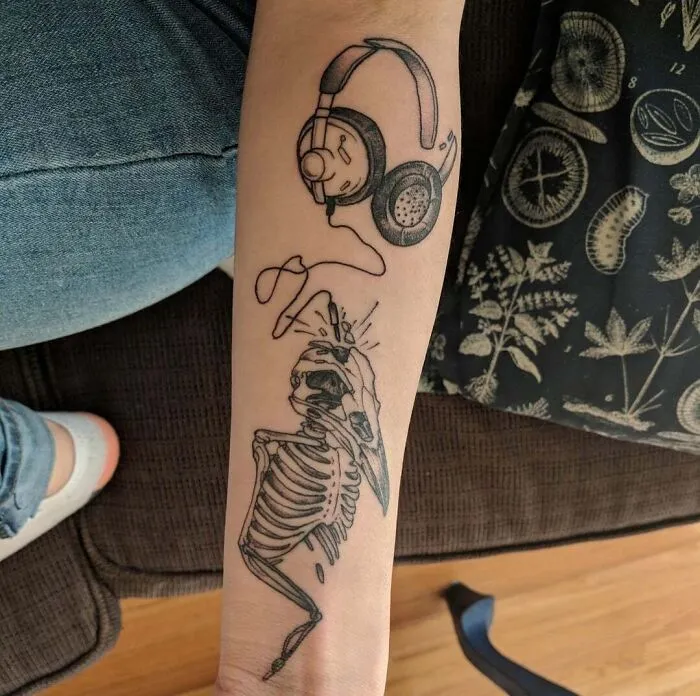 Skeleton and headphones music tattoo on forearm.