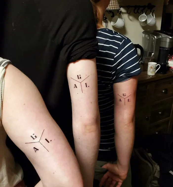 Three people with matching family tattoos on their arms, symbolizing unbreakable bonds.