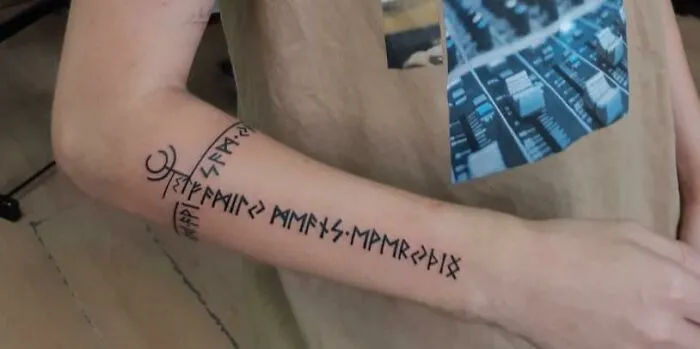 Arm tattoo in runic script symbolizing family bonds.