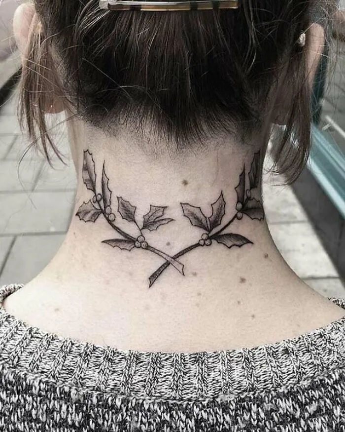 Neck tattoo of holly branches, symbolizing family bonds.