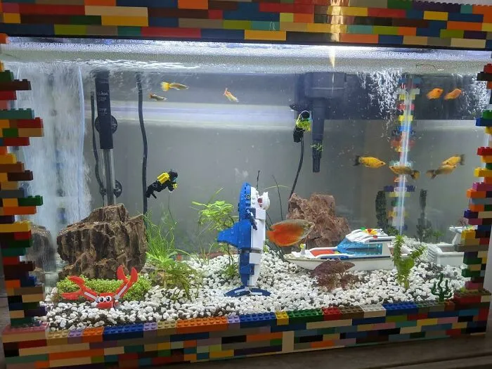 Aquarium idea with LEGO frame, colorful fish, a toy shark, and plants for a playful underwater scene.