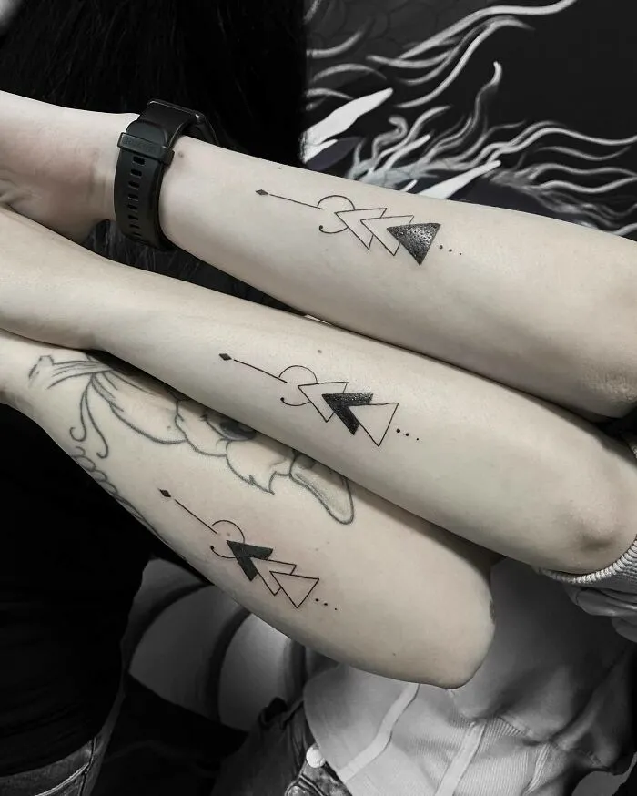 Matching arrow tattoos symbolizing family bonds on three forearms.