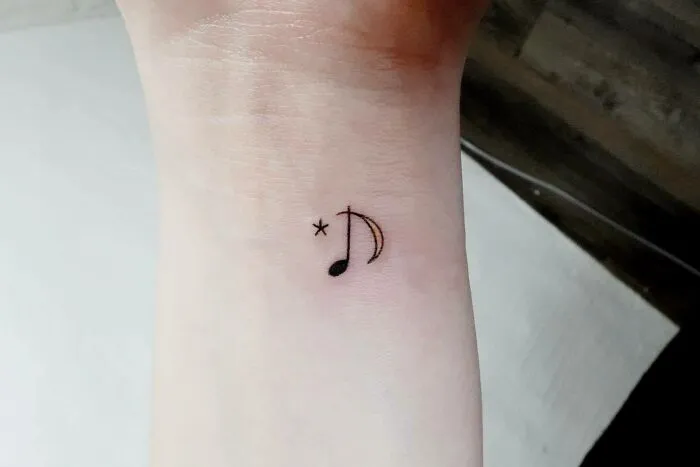 Minimalist music tattoo of a note and star on a wrist.