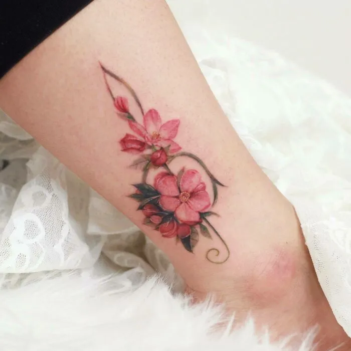 Pink floral tattoo design on ankle, showcasing artful ink style.
