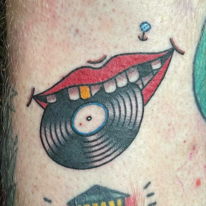 Vinyl record tattoo integrated with lips, a unique music tattoo design on skin.