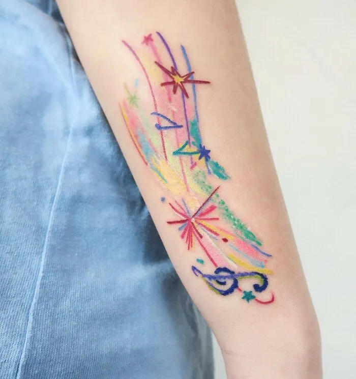 Colorful tattoo featuring stars and a treble clef design on forearm, representing music tattoos.