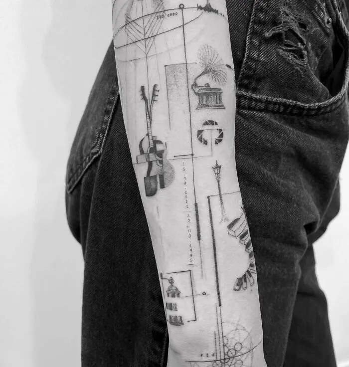 Detailed music tattoos on a person's forearm, featuring abstract instruments and geometric designs.