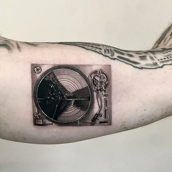 Turntable tattoo on arm, showcasing detailed music-themed ink art.