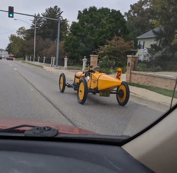 Este tipo conduciendo un coche de carreras de estilo antiguo alrededor de mi ciudad. Tiene la ropa a juego y todo