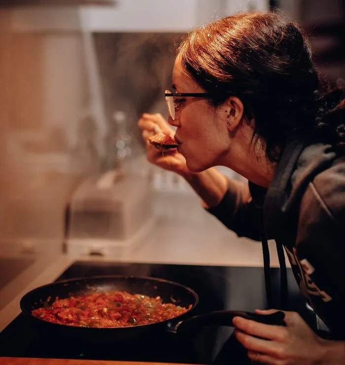 Woman Tasting Food In The Process Of Making It 