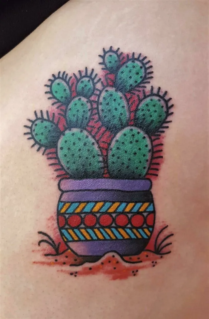 Colorful American traditional cactus tattoo in a patterned pot.