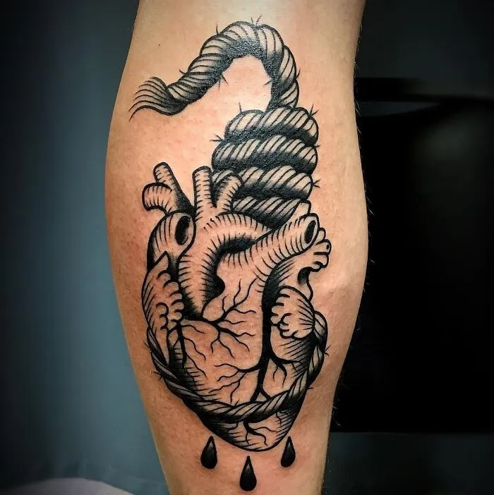 American traditional tattoo of a heart with a rope, shaded in black ink, on a person's calf.