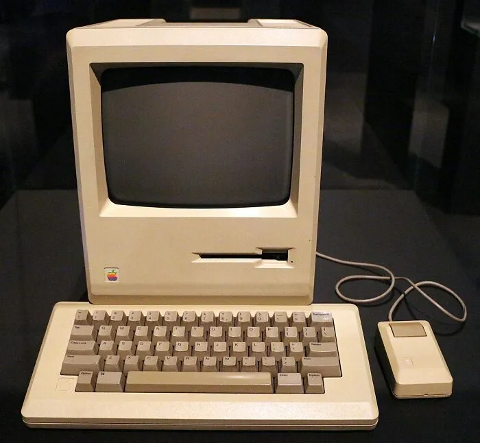 Vintage Apple Macintosh computer with keyboard and mouse, a classic example of old gadgets that were trendsetters in technology.
