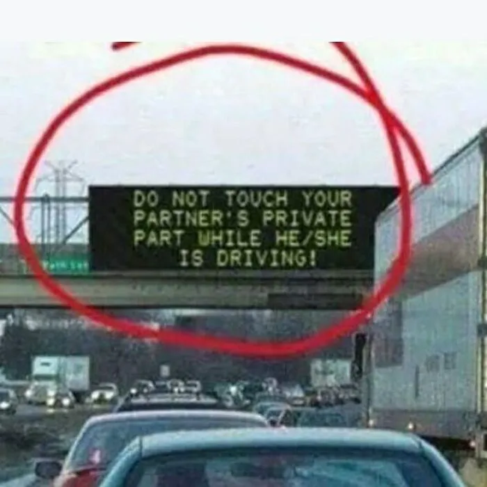 Funny sign on a highway warns drivers about distracting behavior while driving.