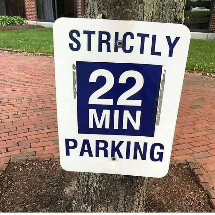 Funny sign showing "Strictly 22 Min Parking" mounted on a tree.